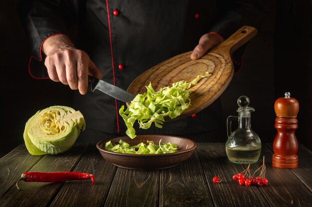 El chef prepara ensalada de col fresca en la cocina.