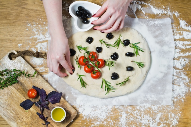 El chef prepara Focaccia, pone aceitunas en la masa.