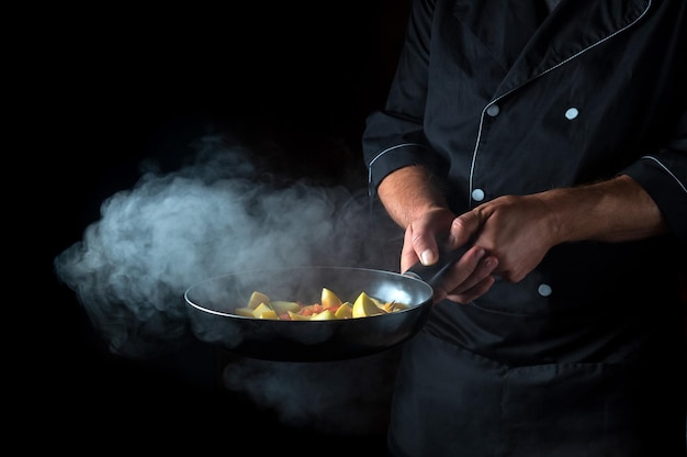 Chef prepara legumes na frigideira Cozinhar comida vegetariana saudável e refeição em fundo escuro