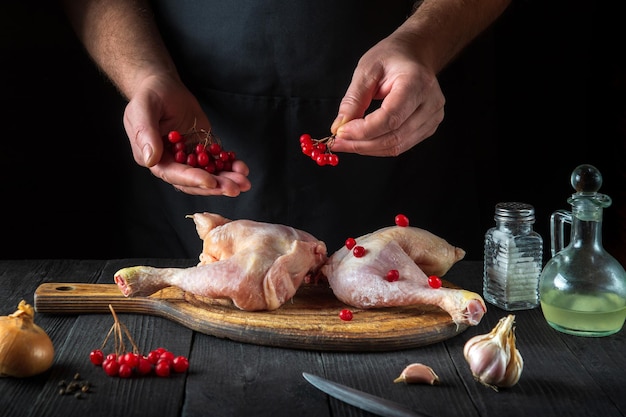 El chef prepara muslos de pollo crudo en la cocina del restaurante.