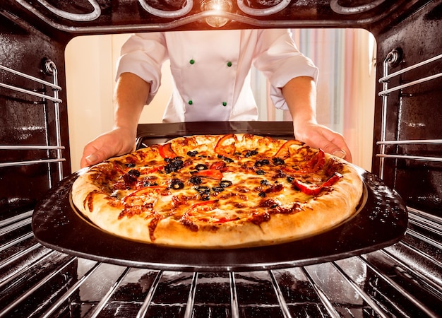 Foto chef prepara pizza no forno, vista de dentro do forno. cozinhar no forno.