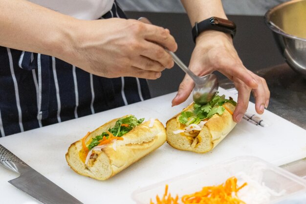 El chef prepara un sándwich en la cocina. Un sándwich delicioso con verduras y carne.