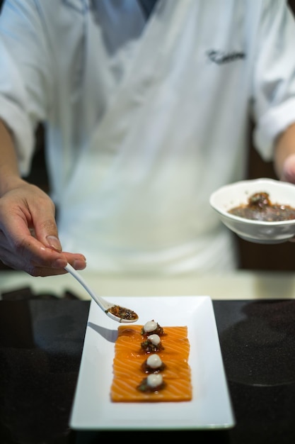 El chef prepara el sashimi de salmón el proceso de hacer y decorar el sashimí de salmó