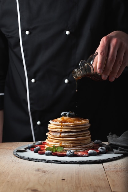 El chef prepara tortitas con frutos del bosque.