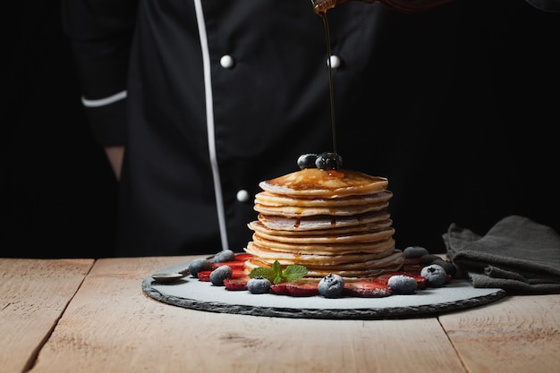 El chef prepara tortitas con frutos del bosque.