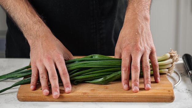 Foto el chef preparando con cebolla de primavera en la tabla de cortar