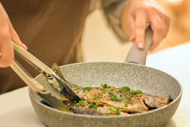 Chef preparando deliciosos peixes na frigideira