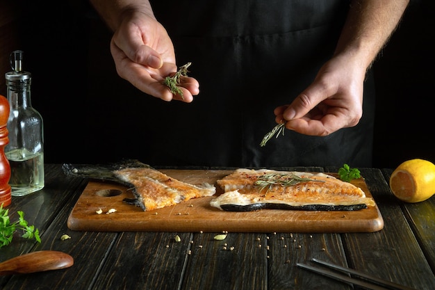 Chef preparando pescado rojo fresco en la mesa de la cocina en un restaurante Antes de freír los filetes de pescado se sazonan con aromático romero cocina europea