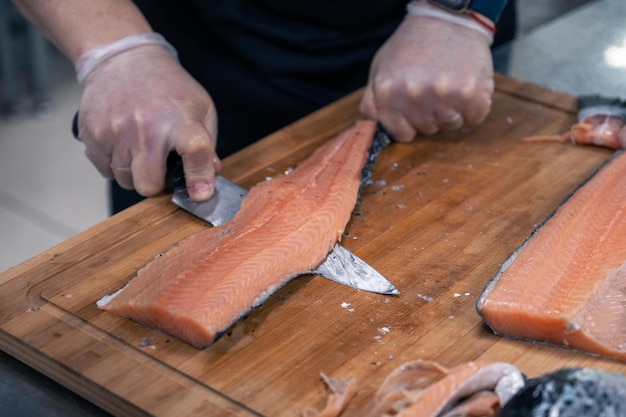 Chef preparando un pescado salmón destripando y fileteando en la cocina