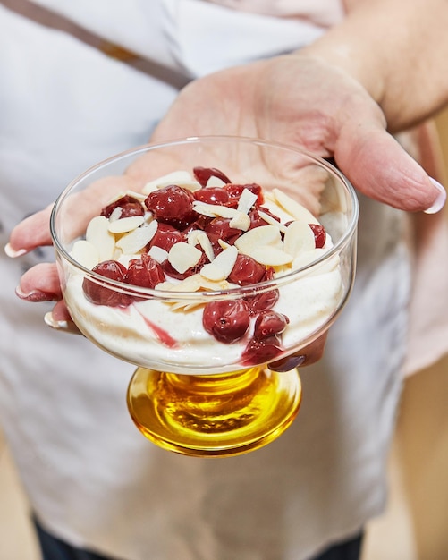 Chef preparando un postre especial con galletas de cereza y nueces de crema fresca en un vaso