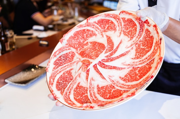 Foto el chef presenta la carne de vacuno rare slices kagoshima wagyu con una textura de mármol alto.