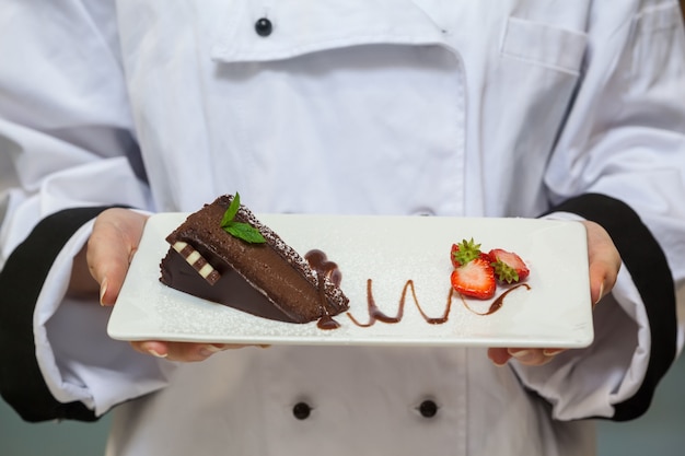 Chef presenta pastel de chocolate con fresas