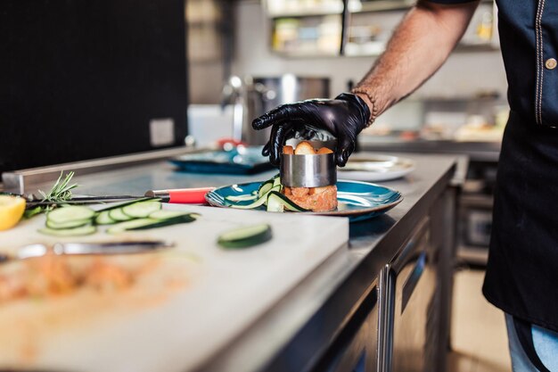 Chef profesional en la cocina del restaurante preparando una deliciosa comida con carne y verduras.