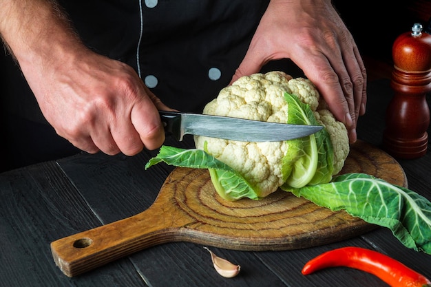 Chef profesional corta coliflor en la cocina de un restaurante antes de cocinar