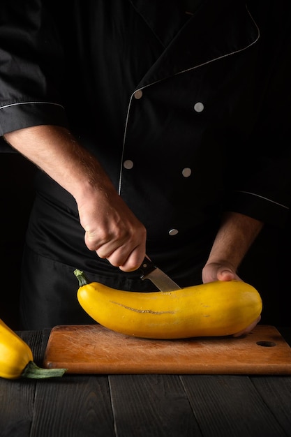 El chef profesional corta la médula amarilla madura con un cuchillo El calabacín frito es una gran dieta para el desayuno o el almuerzo Ambiente de trabajo en la mesa de la cocina del restaurante