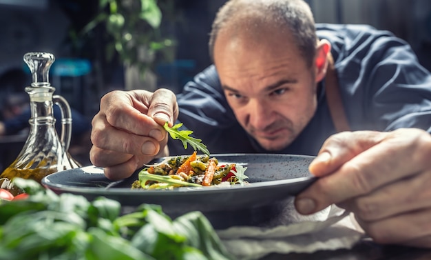 Un chef profesional decora una comida justo antes de servirla a un cliente en un restaurante, pub u hotel.