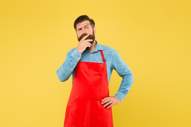 Chef profesional Guapo barista masculino está trabajando camarero maduro su nuevo chico de negocios en uniforme de asistente de tienda soñando hombre con delantal rojo sobre fondo amarillo Expresión segura