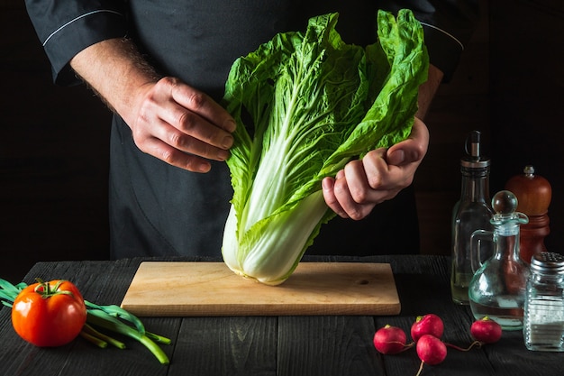 El chef profesional prepara una ensalada fresca de repollo napa. Preparación para cortar en rodajas en la cocina del restaurante. Idea de dieta vegetal.