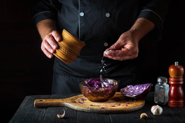 Chef profesional rocía la ensalada con sal de col roja fresca