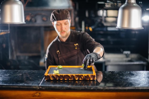 Un chef profesional sirve maravillosamente un jugoso bistec a la parrilla con mantequilla y condimentos. Carne a la brasa en un restaurante.