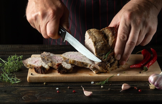 Chef profissional cortando carne bovina grelhada em uma tábua