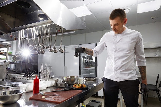 Chef profissional cozinhando na cozinha moderna de restaurante de hotel preparando salada de camarão