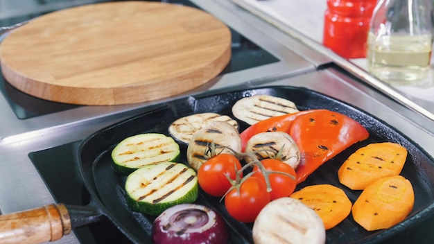 Un chef que trabaja en la cocina calentando los champiñones y las verduras en la sartén sin aceite