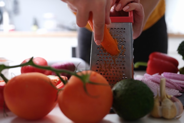 Chef ralando cenouras para fazer salada de legumes closeup