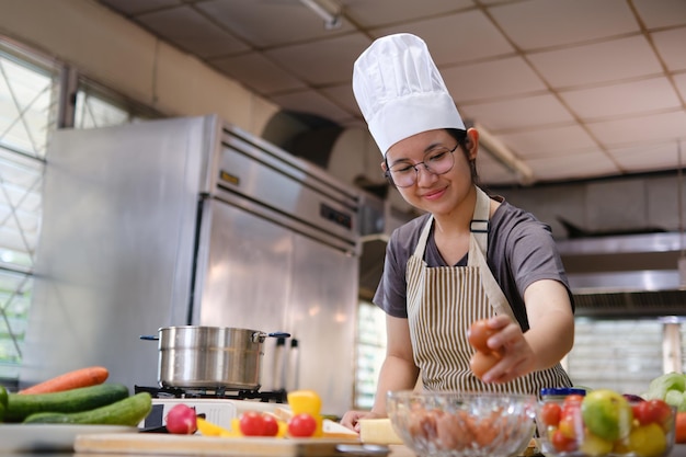 Chef recogiendo huevos marrones frescos de un cuenco de vidrio en una cocina llena de productos coloridos