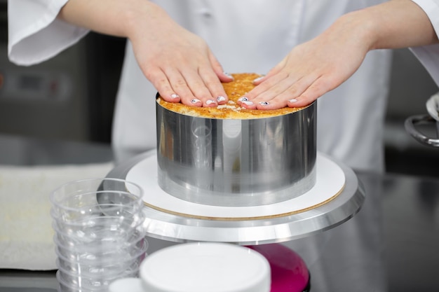 El chef de repostería corta una galleta para armar el pastel.