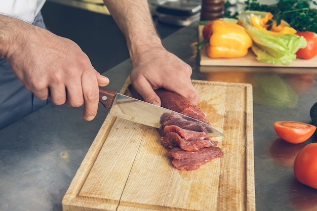 Chef de restaurante japonés masculino cocinando en la cocina cortando ingredientes