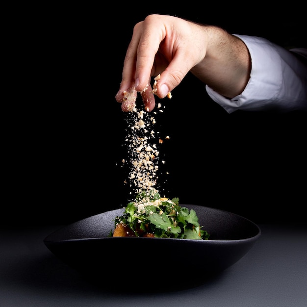 El chef rocía la ensalada con nueces.