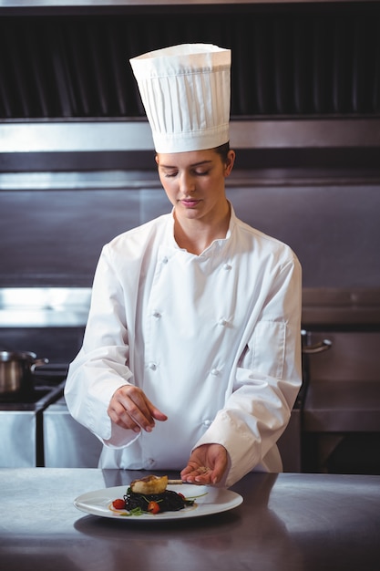 Chef rociando especias en el plato