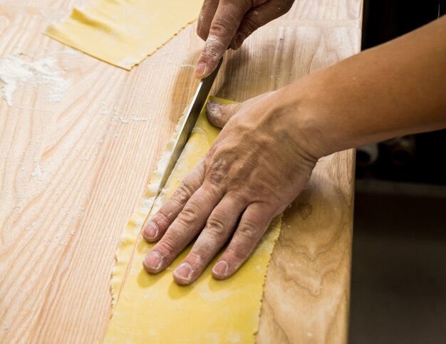 Chef rodando la masa con una máquina de pasta. Máquina para hacer pasta.