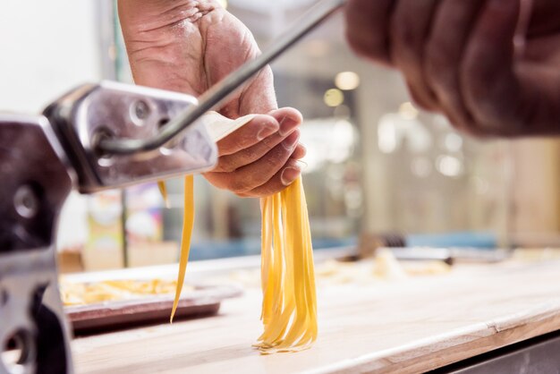 Chef rodando la masa con una máquina de pasta. Máquina para hacer pasta.