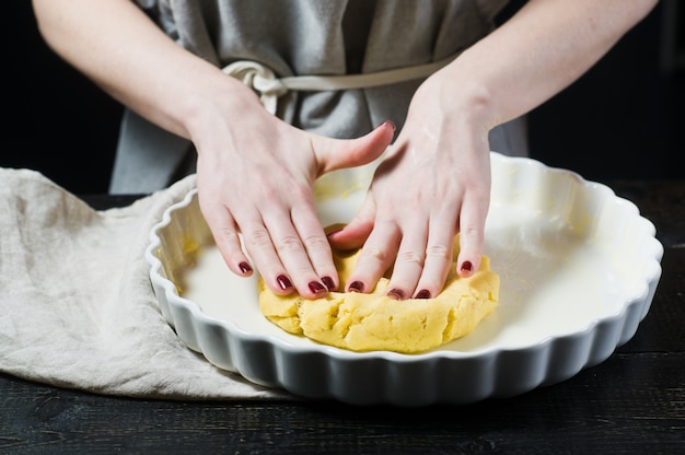 Chef rollt den Teig in einer Auflaufform aus und kocht