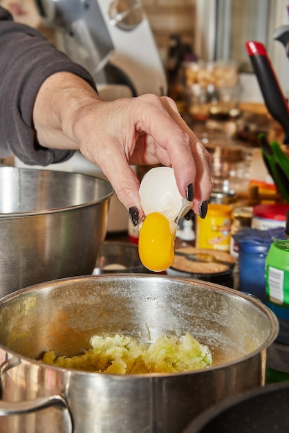 El chef rompe un huevo en un plato que se está preparando en un tazón