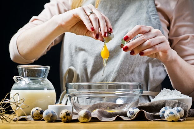 Chef rompe huevos de codorniz en un tazón. El concepto de repostería de cocina.