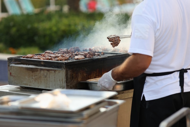 El chef saca los cortes de carne fritos con pinzas de la parrilla y los coloca en un plato.