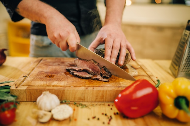 Chef en la sartén con carne asada y verduras