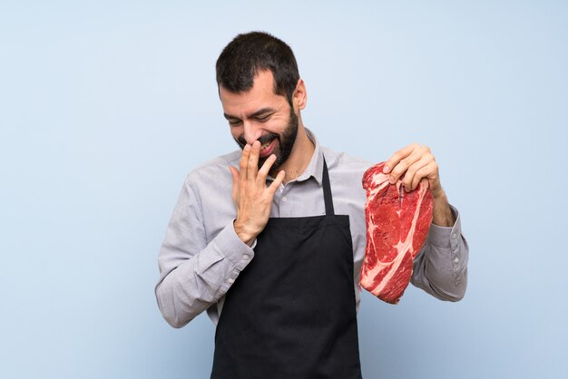 Chef, segurando uma carne crua, sorrindo muito