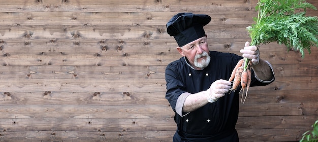 Chef senior en uniforme con verduras en manos