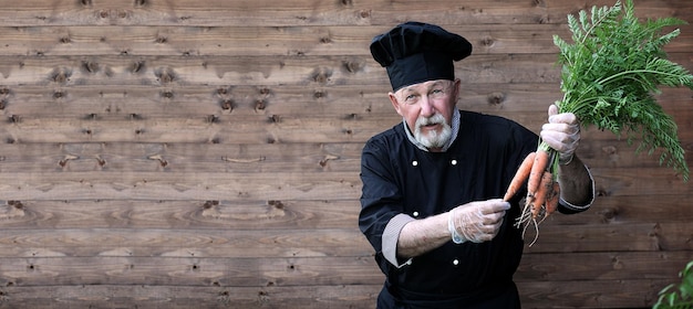 Chef senior en uniforme con verduras en las manos