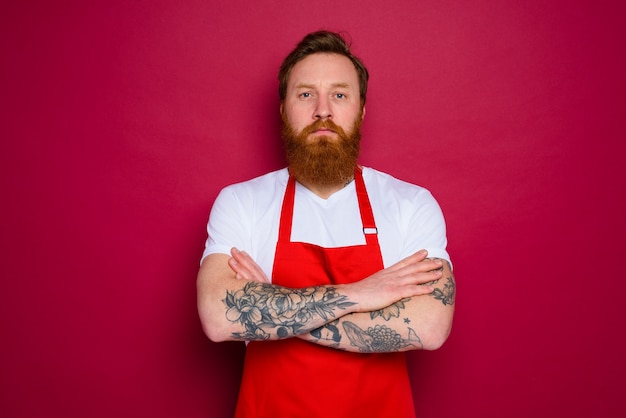 Chef sério e isolado com barba e avental vermelho