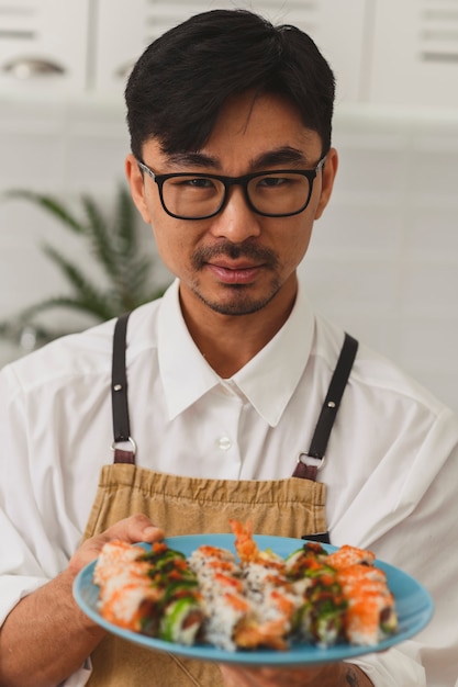 Foto chef serve um conjunto de rolos de sushi em um prato promocional de comida