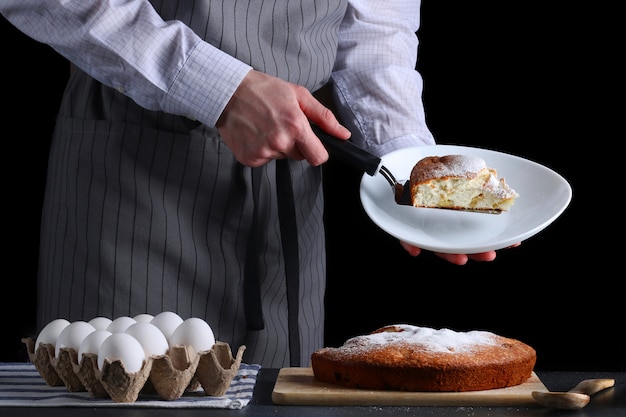 Chef serviert den Kuchen auf dunklem Hintergrund