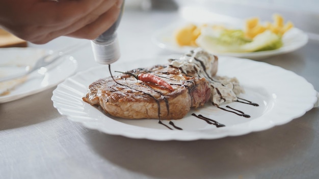 Chef serviert Fleisch auf dem Teller - Paprika und Soße, Nahaufnahme