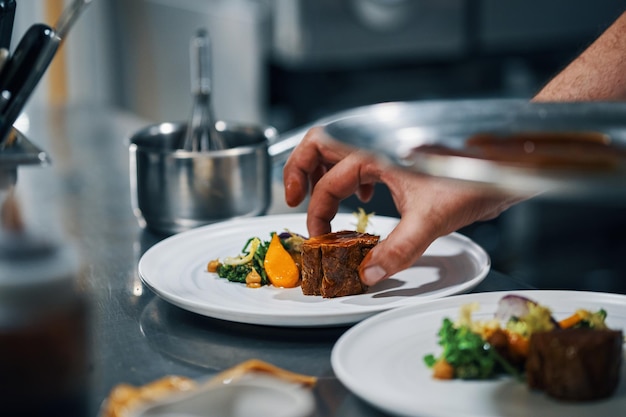 Chef servindo bife na cozinha profissional