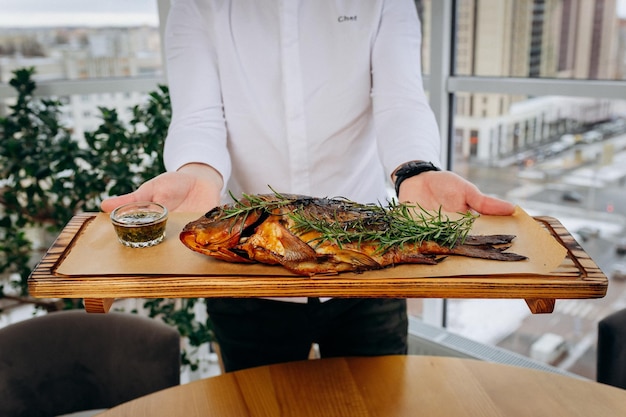 Chef servindo peixe carpa de rio recém-delicioso no salão do restaurante