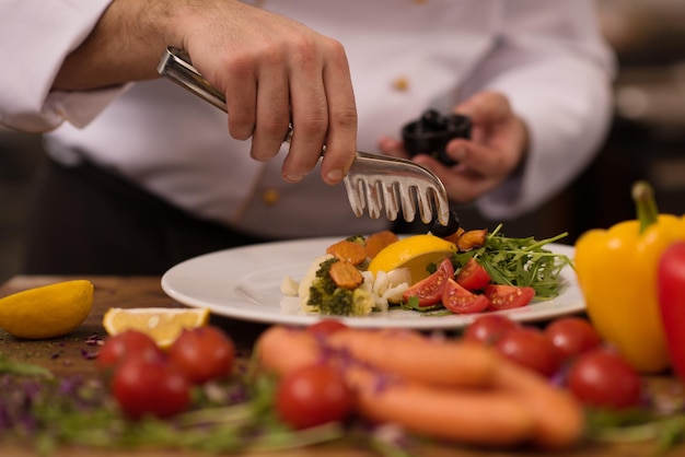 chef servindo salada de legumes no prato na cozinha do restaurante